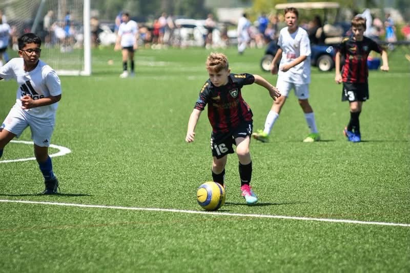 A St. Louis Legends player in a black and red kit dribbling during a match