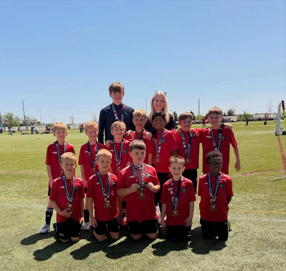 A St. Louis Legends youth team in red shirts poses with medals after a tournament