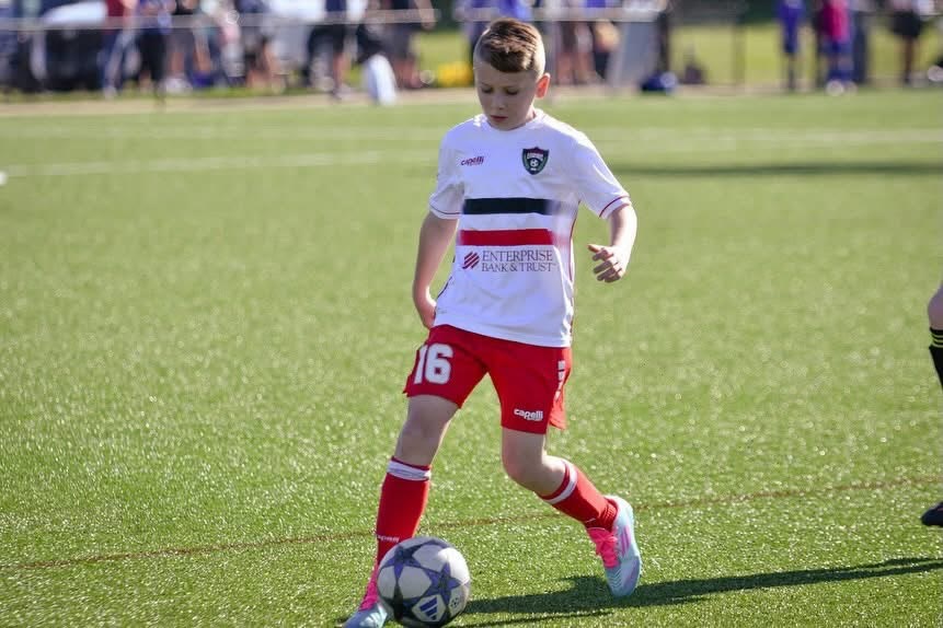 A St. Louis Legends player in a white kit dribbling the ball during a match