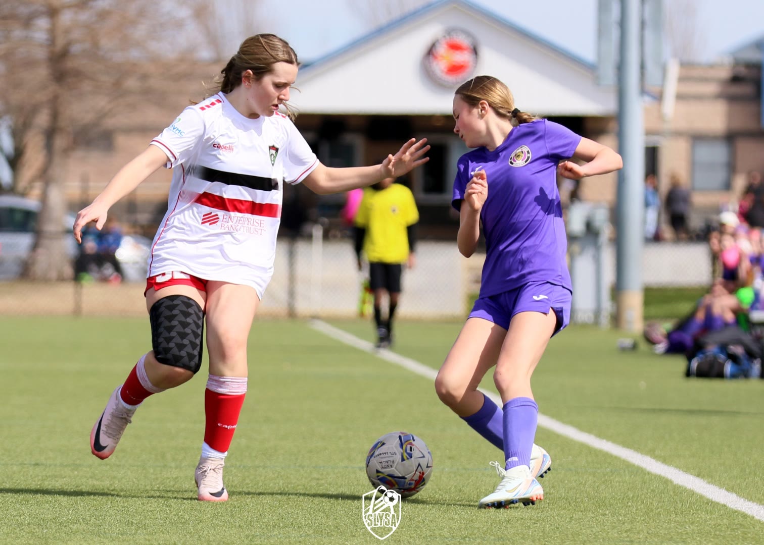 A St. Louis Legends player in a white, red, and black kit dribbling the ball against an opponent on the field